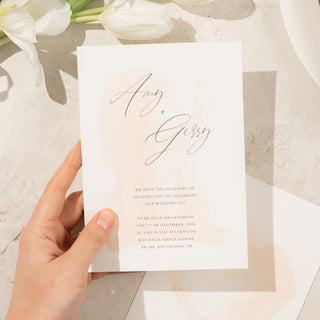 Minimal and romantic wedding invitation close-up with a subtle ombre watercolor design in delicate, soft tones.