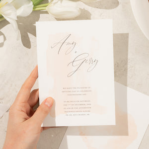 Minimal and romantic wedding invitation close-up with a subtle ombre watercolor design in delicate, soft tones.