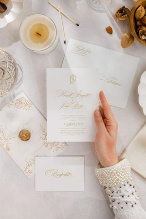 Luxurious wedding invitation suite with a regal monogram and handmade floral watercolor illustrations, complemented by a vellum gate.