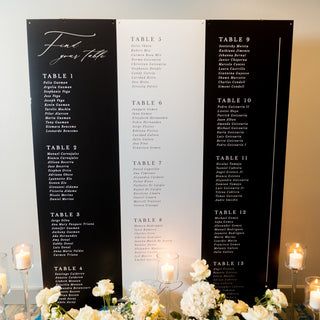 Seating chart for a wedding with black boards and white flowers on a table.