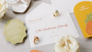 Wedding invitation set with shoes, rings, and flowers on a light surface
